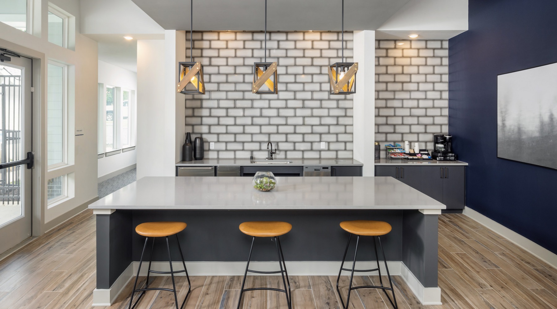 Resident lounge and kitchen at Prose New Hope Apartments for rent in Raleigh, NC, featuring wood grain floor paneling.
