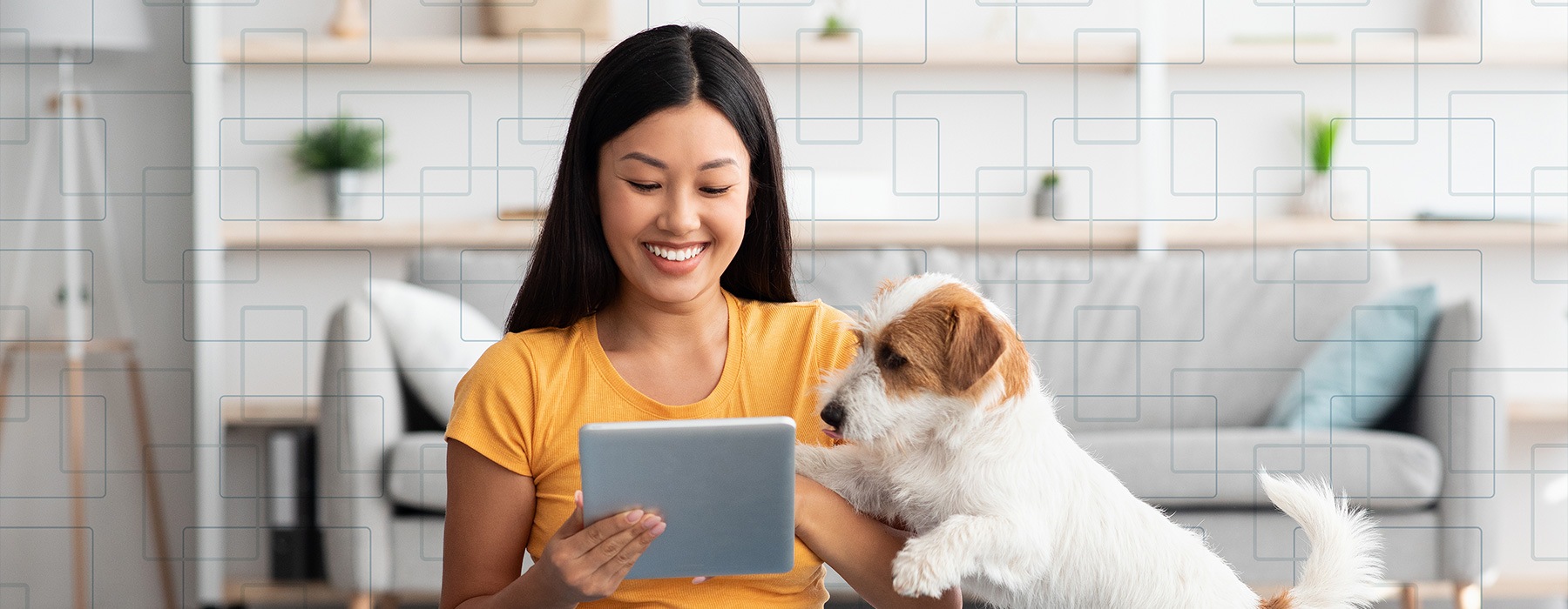 lifestyle image of a woman smiling, working on a smart device beside her pet